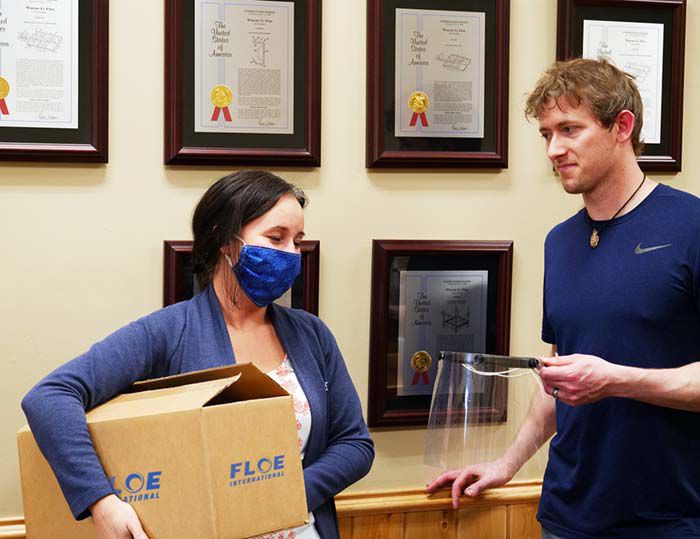 Katie Nelson of Riverwood (left) picks up face shields made by FLOE’s Shawn Hagen.